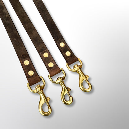 Three Covert Canine Co. 4ft leather leads showing solid brass swivel snap hooks, each secured with a stitched and riveted joint