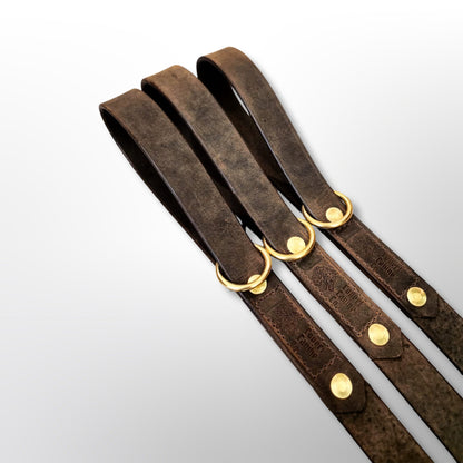 Handle ends of three Covert Canine Co. 4ft leather leads with solid brass floating rings and the Covert Canine Co. logo stamp