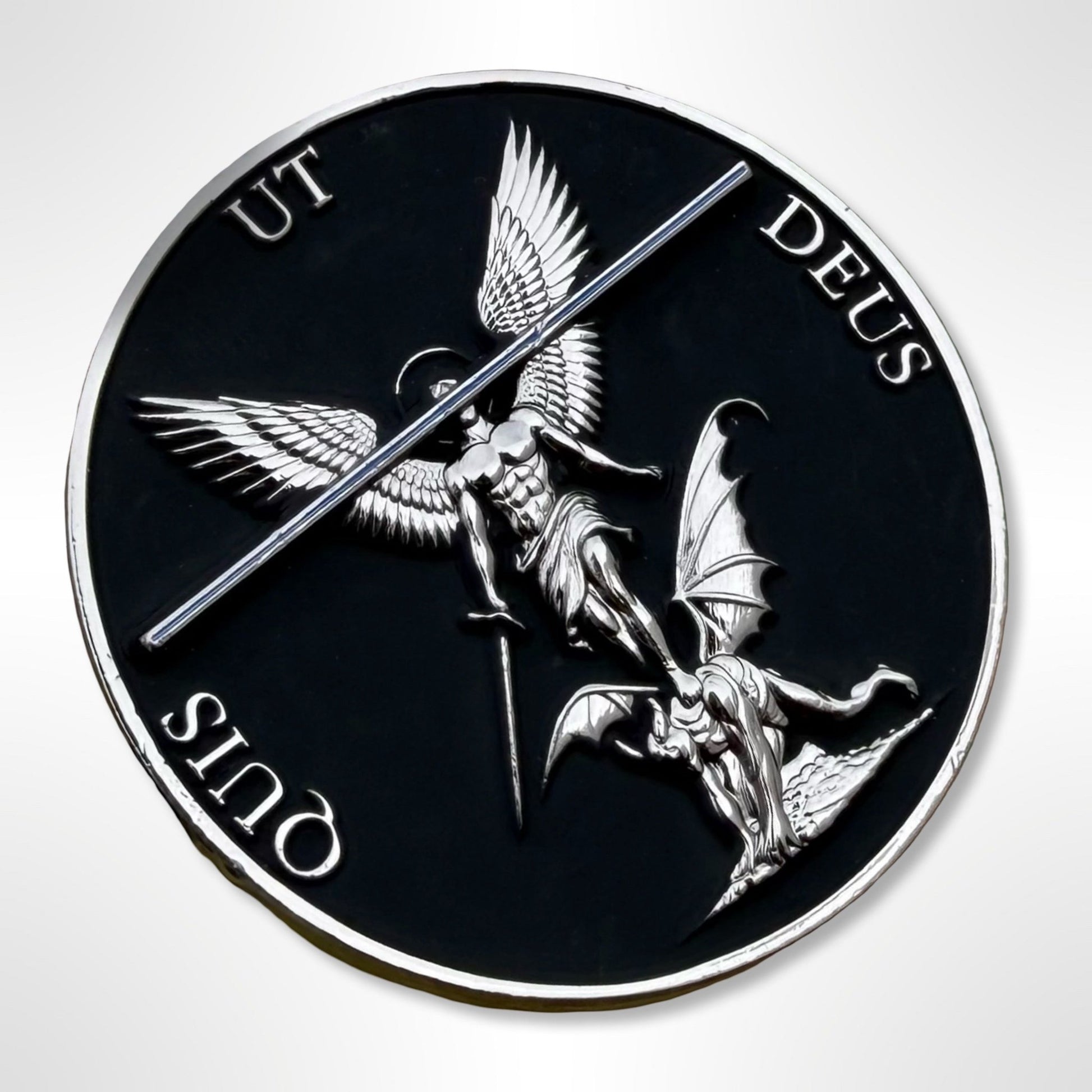 Circular emblem with winged figure and bat-like creature, featuring Latin text on a black background.